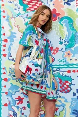 Bolso tote de tela estampada con motivos florales y geométricos en tonos azul, verde, rojo y blanco. Tiene doble asa de hombro y cierre con cordón ajustable con cuentas de madera.