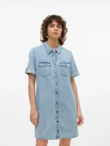 Vestido corto de denim en tono celeste claro, con cuello camisero, cierre frontal con botones metálicos, bolsillos con solapa en el pecho y mangas cortas con vuelta.