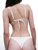 Bombacha de bikini tipo less color negro con tiras finas ajustables en los laterales y detalle de placa metálica con logo en la parte trasera.