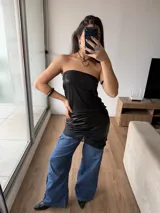 Vestido corto tipo strapless de efecto cuero negro, con detalle de puntilla en el ruedo.