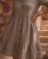 Vestido corto verde militar de lino, con cuello mao, escote en V con botones, mangas tres cuartos acampanadas con volados y falda con volado en el ruedo.