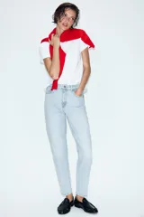 Jeans tipo mom fit de tiro alto color blanco, con diseño de cinco bolsillos, cierre frontal con cremallera y botón, y corte tobillero.
