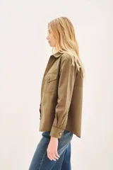 Campera de estilo militar color verde oliva, con corte regular, bolsillos frontales tipo plaqué y cierre frontal con botones metálicos.