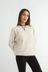 Buzo de tejido de punto en color beige jaspeado, con cuello redondo y detalles de costura en contraste en el cuello y el ruedo.