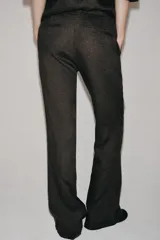 Pantalón flare de tiro medio confeccionado en lino color marrón. Cuenta con cintura con trabillas, bolsillos delanteros, perneras de corte evasé y cierre frontal con cremallera y botón.