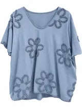 Remera holgada color azul jean, con cuello en V, mangas cortas y detalle de flores en relieve bordadas en hilo tipo toalla distribuidas por toda la prenda.