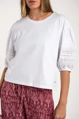 Remera negra de algodón con mangas tres cuartos abullonadas y detalle de bordado calado tipo ojal en la zona del antebrazo.