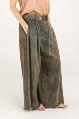 Pantalón palazzo de denim con doble pinza, tiro alto y pierna extra ancha con ruedo deshilachado. Presenta un efecto de teñido degradé irregular en tonos verde militar y marrón, cierre con botón y bolsillos laterales.