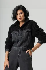 Campera corta de denim negro combinada con corderito sintético negro en cuello y mangas. Presenta cierre frontal con botones metálicos y bolsillos frontales con solapa.