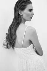 Vestido midi de color blanco con textura arrugada, escote en V, breteles finos y detalle drapeado en el busto.