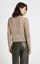 Cárdigan de punto beige con diseño calado y texturizado. Presenta cuello redondo, mangas largas y cierre frontal con botones a tono.