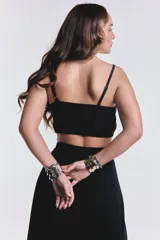 Top negro crop con tiras regulables, escote en V y detalle de nudo frontal con pequeña abertura.