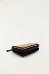 Billetera rectangular color marrón con textura tejida, cierre perimetral con cremallera y bordes decorados con costura en zigzag negra. Cuenta con el texto bordado 'Rio' en tonos violeta y verde con una palmera y un tucán integrados.