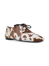 Zapato acordonado de estilo oxford con acabado en pelo sintético estampado con diseño de manchas de vaca en tonos marrón y blanco.