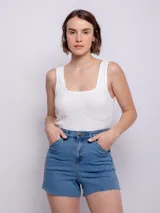 Short de jean azul con cuatro bolsillos, presillas, terminación desflecada, botón y cierre metálico.