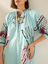 Túnica celeste con estampado de motivos botánicos en rojo y negro.