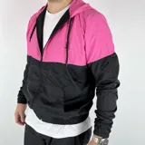 Campera deportiva con capucha, combinada en fucsia y negro, con cierre frontal y bolsillos laterales.