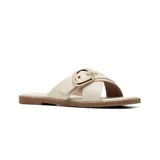 Sandalia plana de estilo casual con tiras cruzadas en el empeine, confeccionada en material sintético color beige. Presenta una hebilla metálica decorativa en tono dorado y suela plana con detalle de costura perimetral.