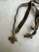 Collar con dije de cruz dorada y cinta de terciopelo color topo.