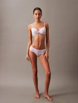 Bombacha tipo hipster de la línea invisible de Calvin Klein, confeccionada en microfibra ligera con bordes cortados a láser sin costuras. Presenta un diseño de talle bajo con cobertura total en la parte trasera y el logo de la marca estampado en la cadera.