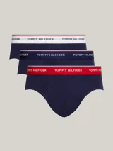 Pack de tres calzoncillos tipo slip de la marca Tommy Hilfiger, confeccionados en algodón elástico, con cintura elástica con el nombre de la marca y líneas distintivas. Incluye una unidad con cintura blanca, otra con cintura azul marino y otra con cintura roja.