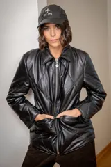 Campera puffer de cuero negro con diseño acolchado en forma de rombos, cierre frontal metálico y cuello camisero.