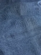 Camisa de manga larga, cuello clásico y fit holgado, confeccionada en tejido de sarga de denim con lavado rinse. Presenta un estampado sutil en la espalda.