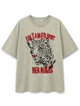 Remera de corte holgado color gris verdoso, con estampa frontal de un leopardo y la frase 'Untamed spirit her rules' en letras rojas.