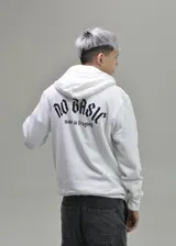 Hoodie blanco con capucha y bolsillo tipo canguro. Presenta un estampado en la espalda con la inscripción 'No Basic' en fuente gótica y debajo el texto 'made in Uruguay'.