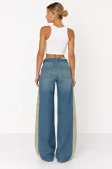 Jeans wide leg de tiro medio, confeccionados en denim azul con franjas laterales en contraste de color beige y diseño de doble cintura.