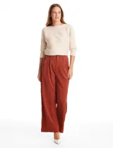 Pantalón tipo palazzo de corte ancho y fluido, confeccionado en tejido sastrero. Presenta tiro alto con doble abotonadura frontal, pinzas decorativas y cintura elástica en la parte posterior. Incluye bolsillos laterales funcionales.