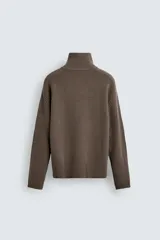 Jersey de punto de corte relajado, color marrón, con cuello perkins y cierre frontal de cremallera. Presenta manga larga y acabados en rib en puños y bajo.