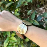 Pulsera elástica con cuentas grandes de resina en tonos marrón, beige y blanco.