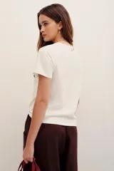Remera de algodón blanca de manga corta y cuello redondo, con aplicación de pedrería formando la palabra "Amour" en el frente.