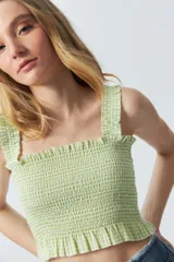 Crop top cuadrillé sin mangas con volados en la cintura.