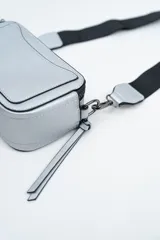 Bandolera de diseño rectangular en color negro, confeccionada en material texturizado. Cuenta con una correa de hombro ajustable y extraíble, cierre superior y tiradores laterales decorativos.