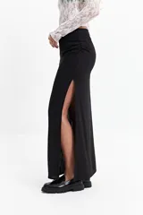 Falda larga negra de calce recto con tajo lateral alto y detalle fruncido en un lateral de la cintura.