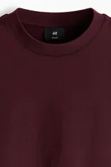 Remera de punto de algodón de peso medio color bordó, con cuello redondo ribeteado, hombros caídos y bajo recto, de corte relajado.