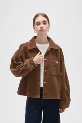 Sobrecamisa de pana color verde oliva oscuro, con cuello clásico, cierre frontal con botones metálicos y dos bolsillos delanteros con solapa y botón.