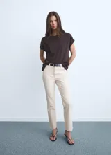 Jeans de tiro medio y corte recto de color marfil, con diseño crop y bajo deshilachado. Presenta cinco bolsillos, trabillas para cinturón y cierre frontal con cremallera y botón metálico.