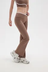 Calza flare de poliamida color negro, con diseño de tiro bajo y detalle de costura cruzada en la cintura.