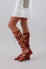 Sandalias gladiadoras rojas con estampado de piel de serpiente, tiras finas y cierre con cordones.
