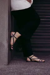 Sandalias planas de cuero negro con múltiples tiras finas adornadas con tachas doradas. Cuentan con cierre de hebilla en el tobillo.