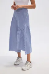 Falda midi de viscosa con estampado de rayas verticales azules y blancas. Presenta un diseño asimétrico con un cruce diagonal en la cintura y un volante fruncido en el ruedo.