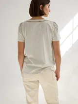 Remera de algodón con escote en V, mangas cortas con frunces en los hombros y detalle de bolsillo frontal con costuras a la vista.