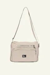 Bandolera color beige con correa larga regulable. Cuenta con múltiples bolsillos con cierre y logo de la marca en etiqueta negra.