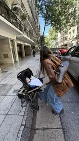 Cartera estilo baguette de cuero con silueta alargada y compacta, diseñada para llevar bajo el brazo. Presenta manijas largas con detalles de nudos esféricos metálicos en las uniones.