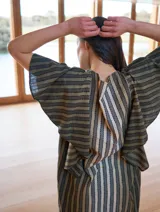 Vestido midi con estampado a rayas verticales en tonos verde oliva, gris y blanco. Tiene cuello redondo y mangas cortas amplias tipo volado.