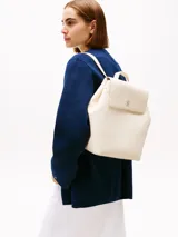 Mochila Tommy Hilfiger color crema con cierre de solapa magnético, asa superior y dos correas ajustables. Tiene un compartimento principal y un bolsillo interior con cremallera.