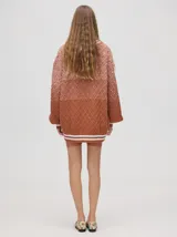 Cardigan de punto con diseño degradé en tonos tierra, patrón de rombos en relieve, cuello en V con cartera de botones y puños con rayas blancas y marrones.